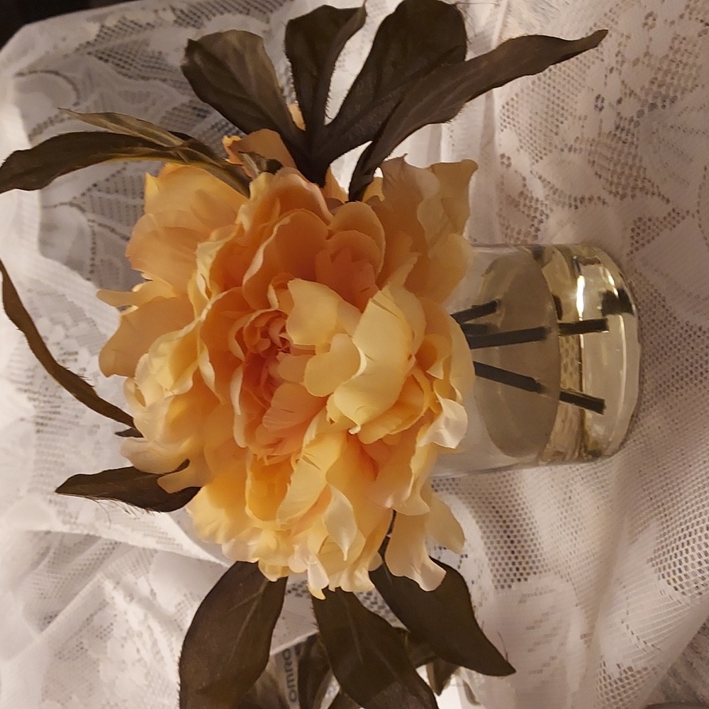 2 Peach color flowers with olive color leaves in fake water in one glass vase